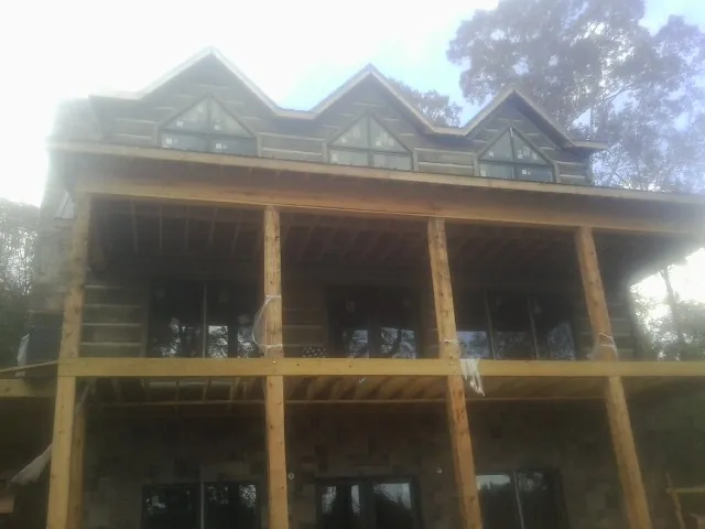 Dormers and porch framing on a large log home under construction — Roof Coating work by our crew in Demarest