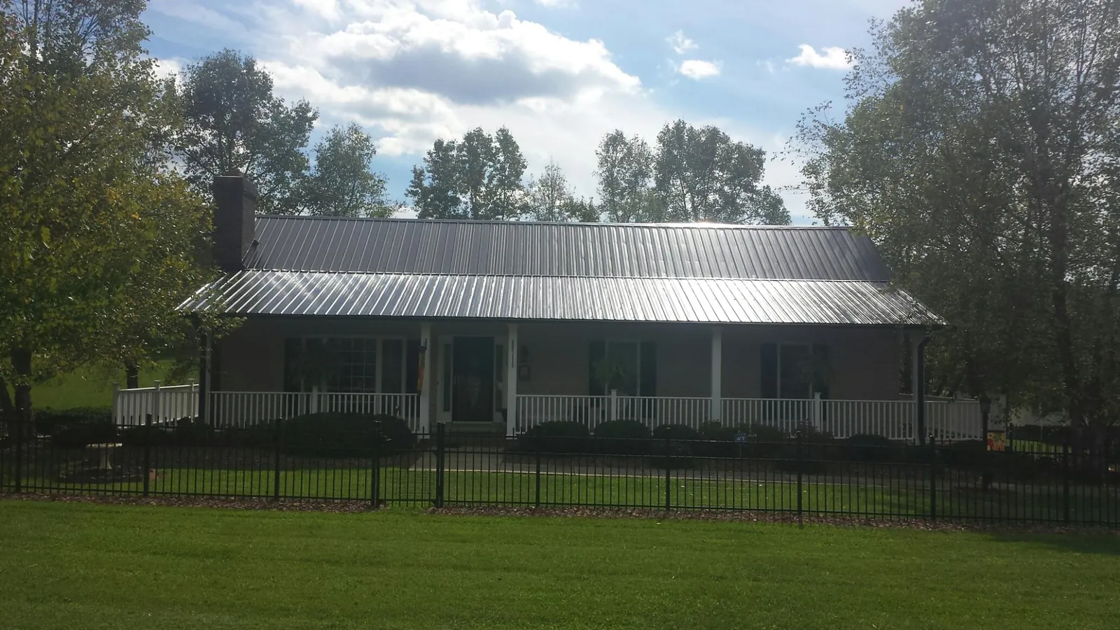 Gray metal roof on a brick ranch with a full width front porch — Gutter Guard Installation work by our crew in Demarest